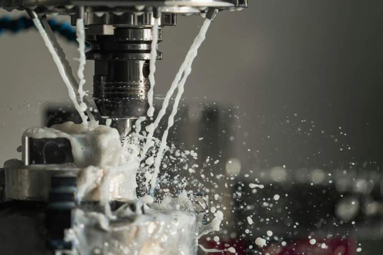 the water is being poured in a cup under a milling machine