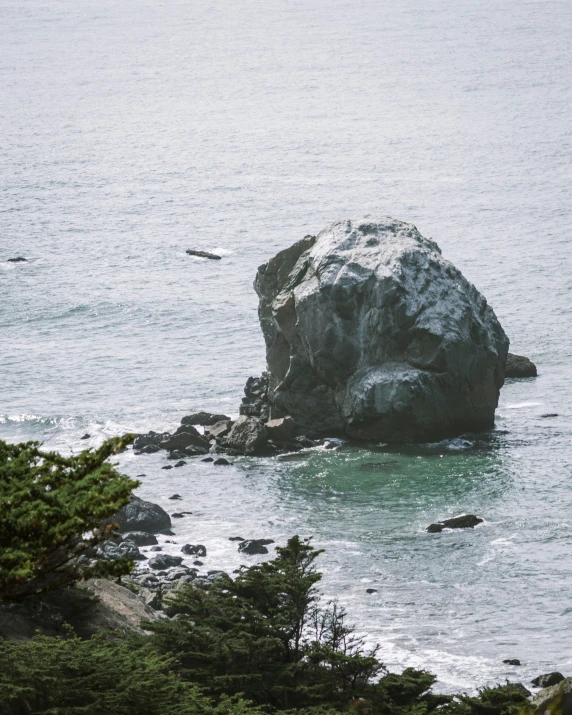 a large rock is standing in the middle of a body of water