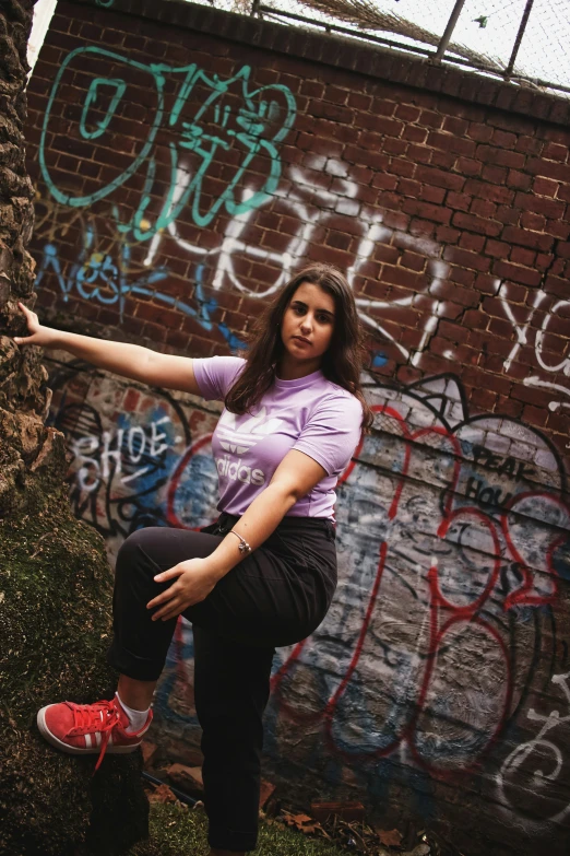 a woman standing by a brick wall covered in graffiti