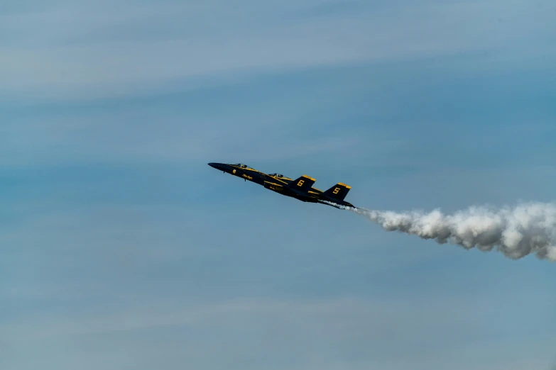 a black and yellow airplane is flying with smoke