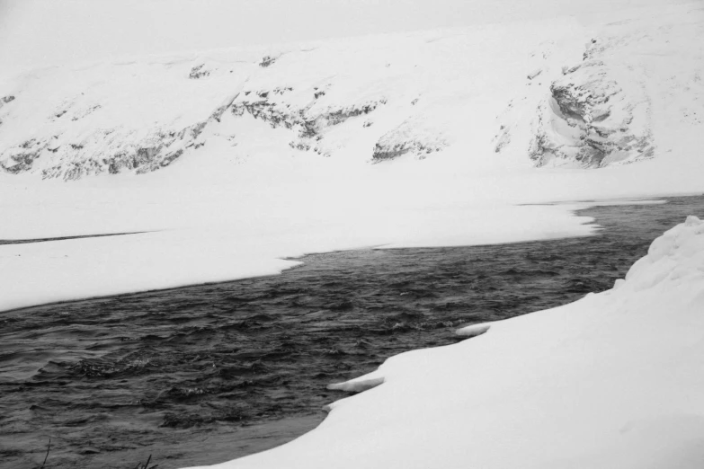 water surrounded by snow with hills in the background