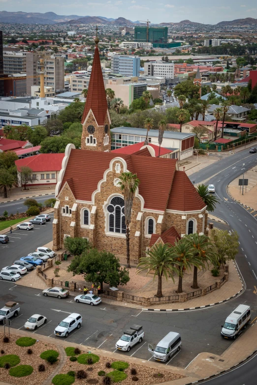 an aerial view of a large church with cars parked nearby