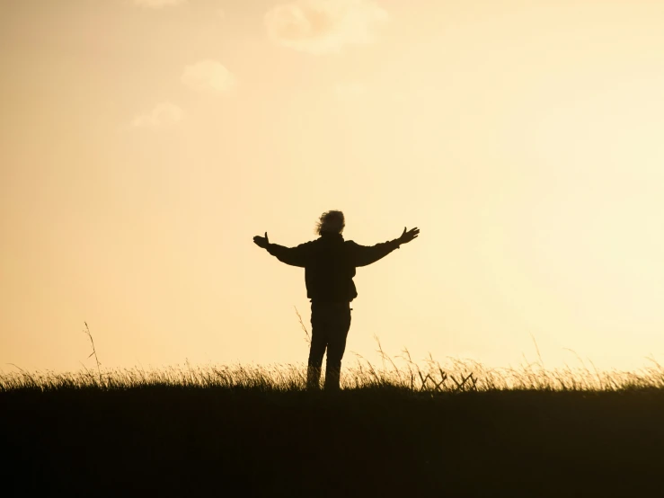 person standing on a hill with their arms open