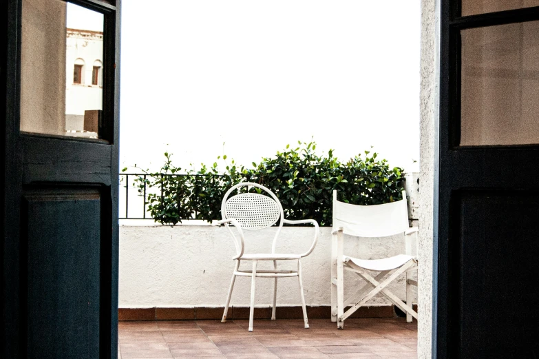 two white chairs with one seat facing the open door