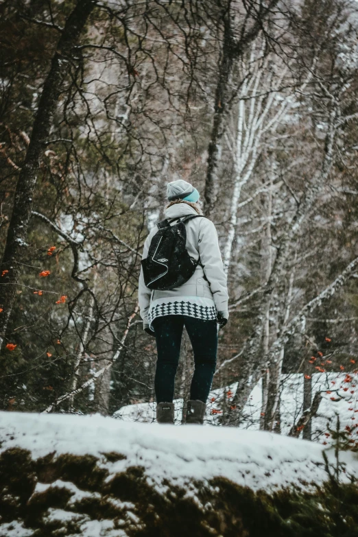 a person wearing a backpack walking across snow covered ground