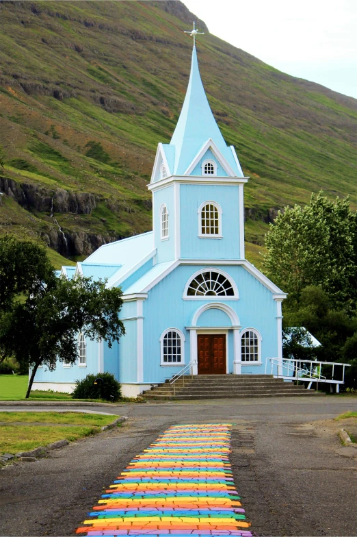 a small blue church with stained wooden chairs in front