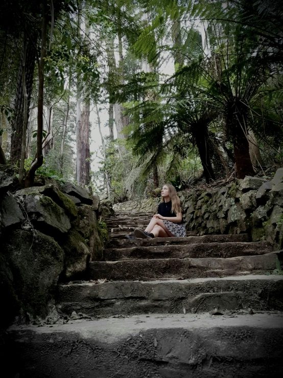 a  sits on some stairs in the woods