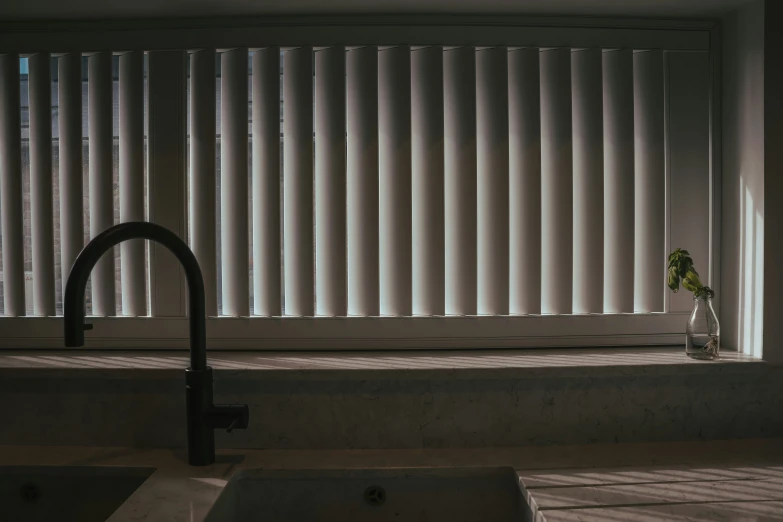 a sink sitting next to a window with blinds on the window