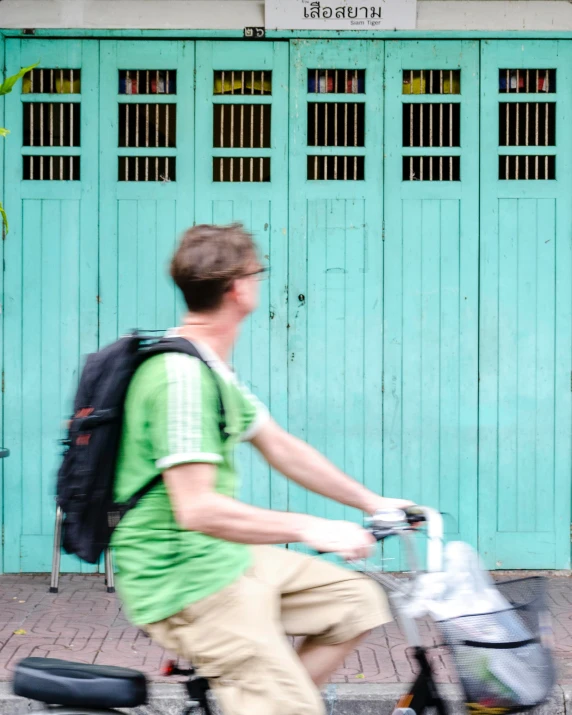 a man riding on the back of a bicycle down the street