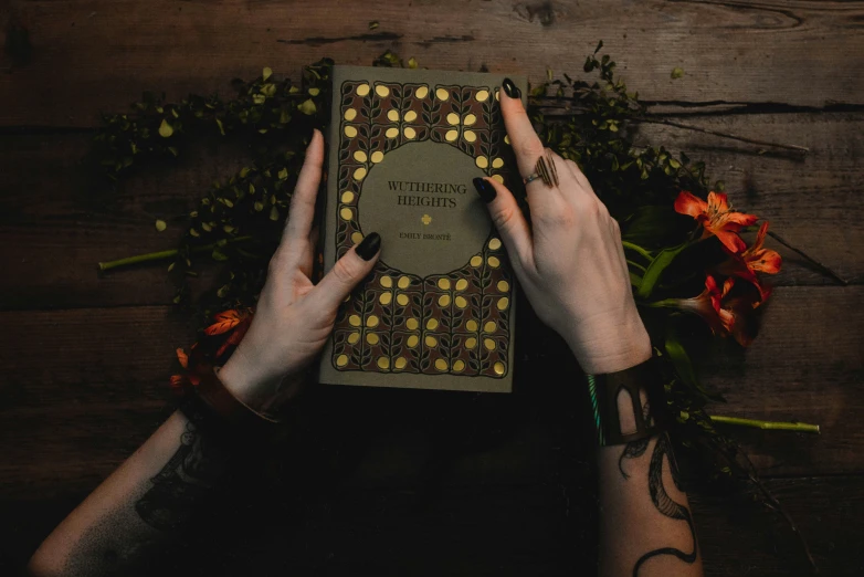 two hands that are over a book on a wooden table