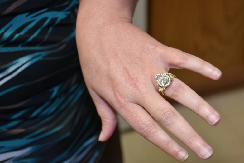 a woman's hand holding a ring with a large green diamond