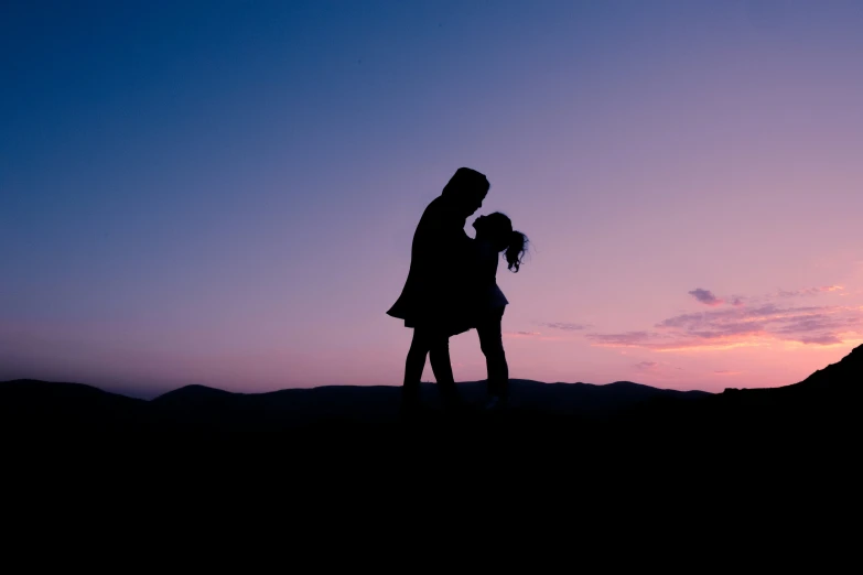 a couple kissing on the side of a hill