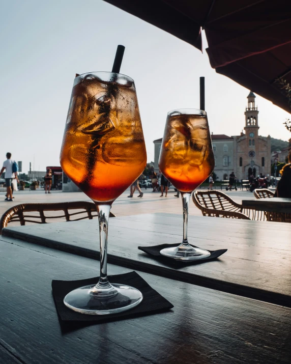 two glasses of liquid are placed on a table with other drinks