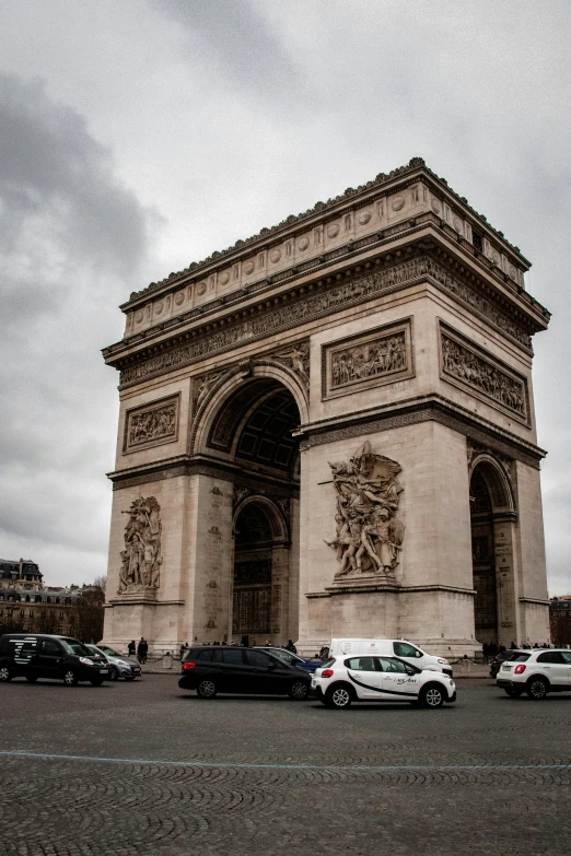 a very large stone arch with many vehicles parked in front