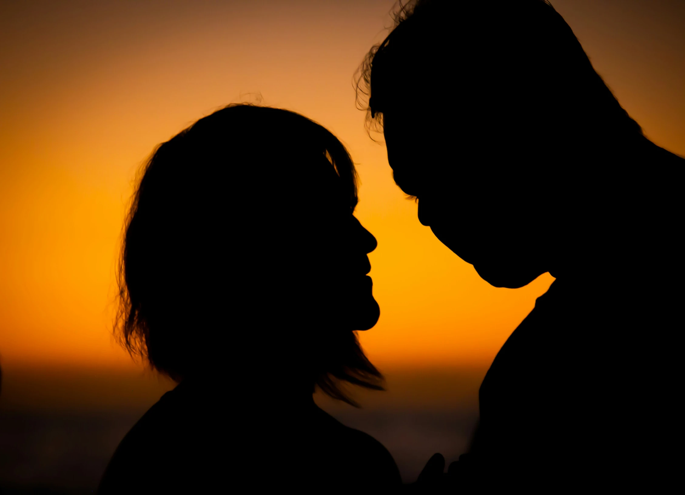 two people face to face in silhouette at sunset