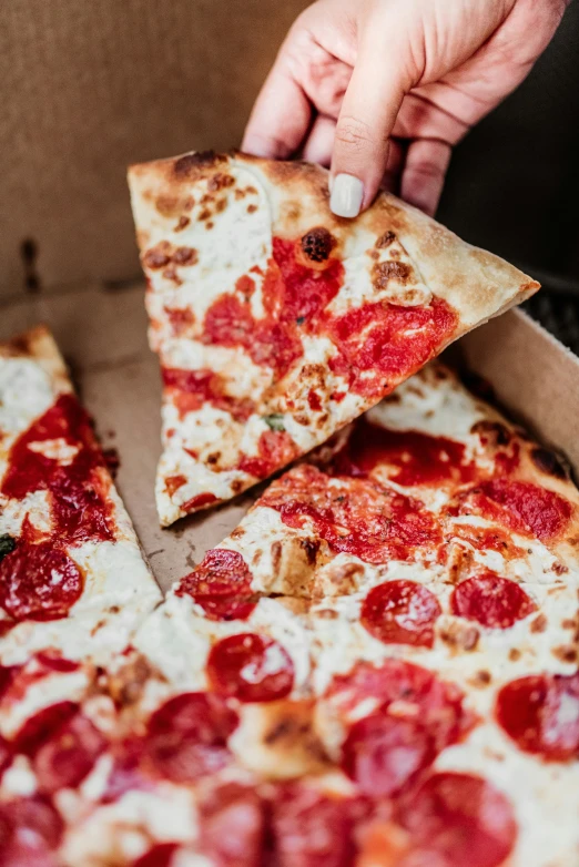 a man is picking up some slices from a pizza