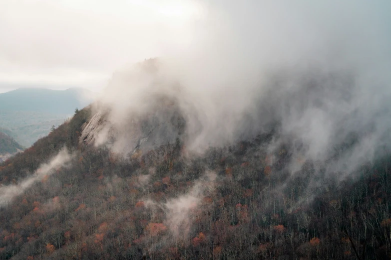 clouds are billowing from the mountains and trees