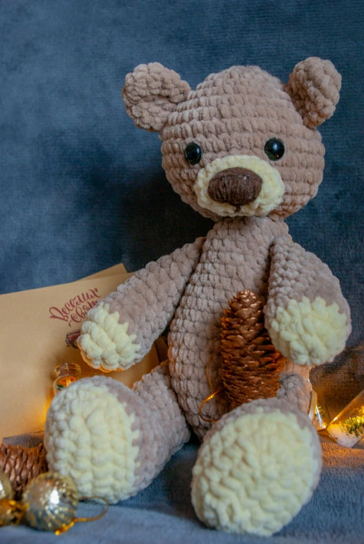 a crochet teddy bear sitting next to christmas lights