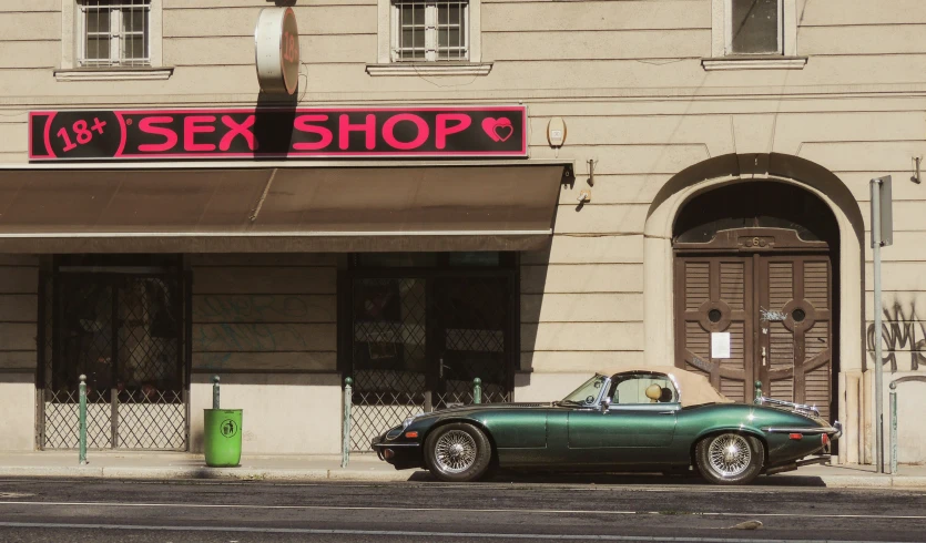 an older car parked in front of a sex shop