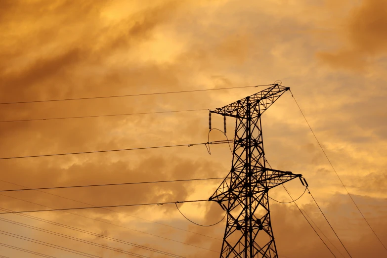 the silhouette of a power tower and some wires