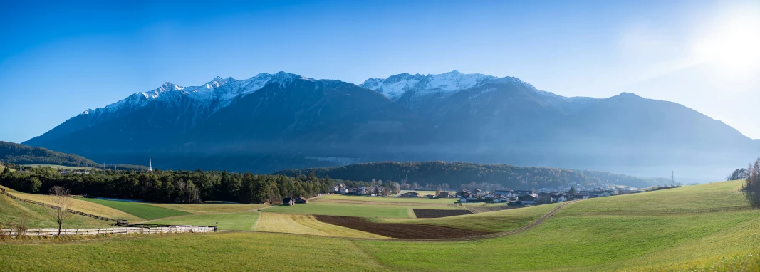 a green landscape with lots of trees and mountains in the background