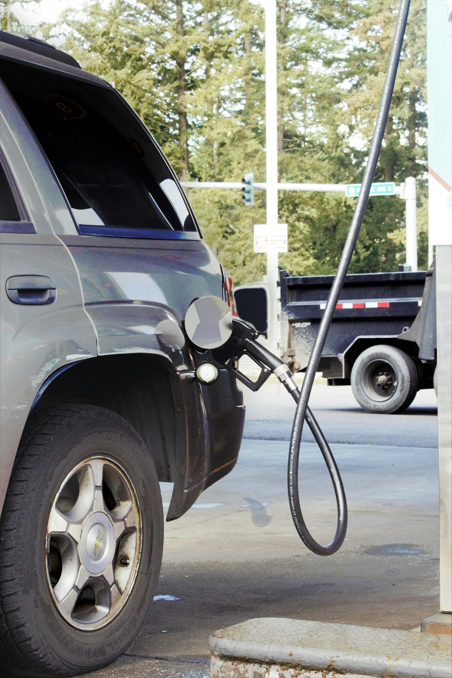 a pickup truck with the hood open and a gas pump hooked up to it