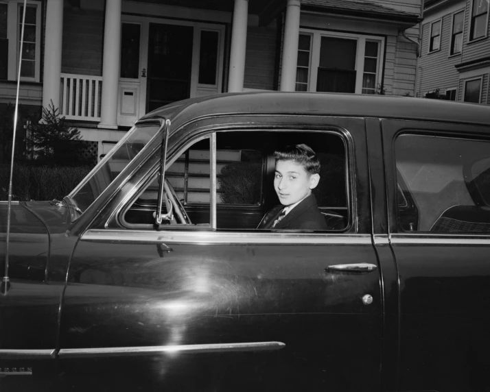 a young man sitting in the back seat of a car