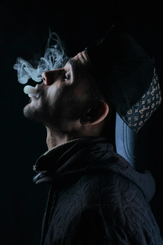 a man standing while smoking soing in the dark