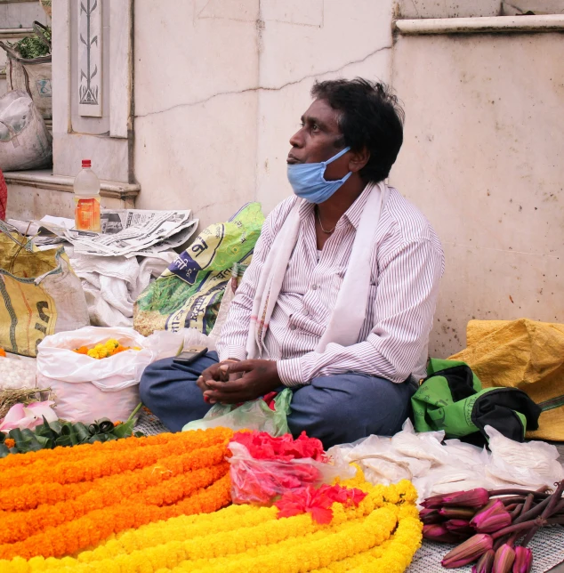 a man sitting in front of a market filled with vegetables