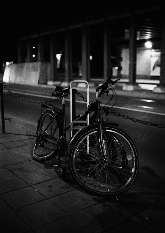 two parked bikes at the street side in black and white