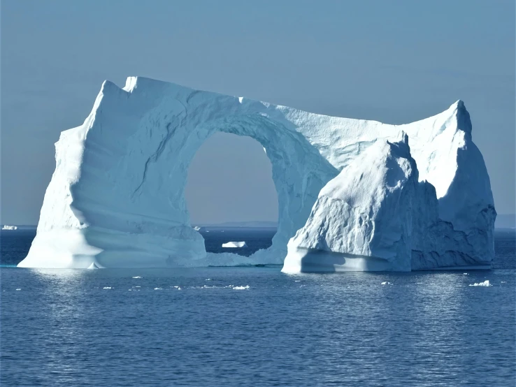 an iceberg with a large arch near water