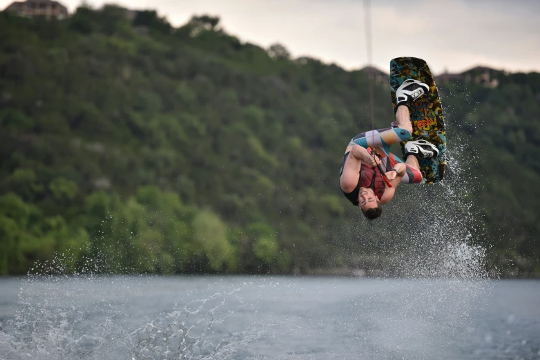 the person is airborne over a lake with his board