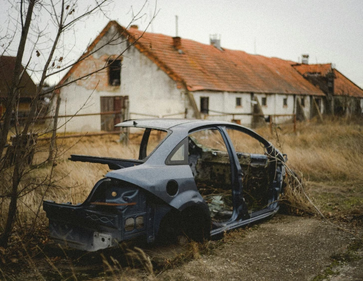 an old abandoned car parked in front of a house