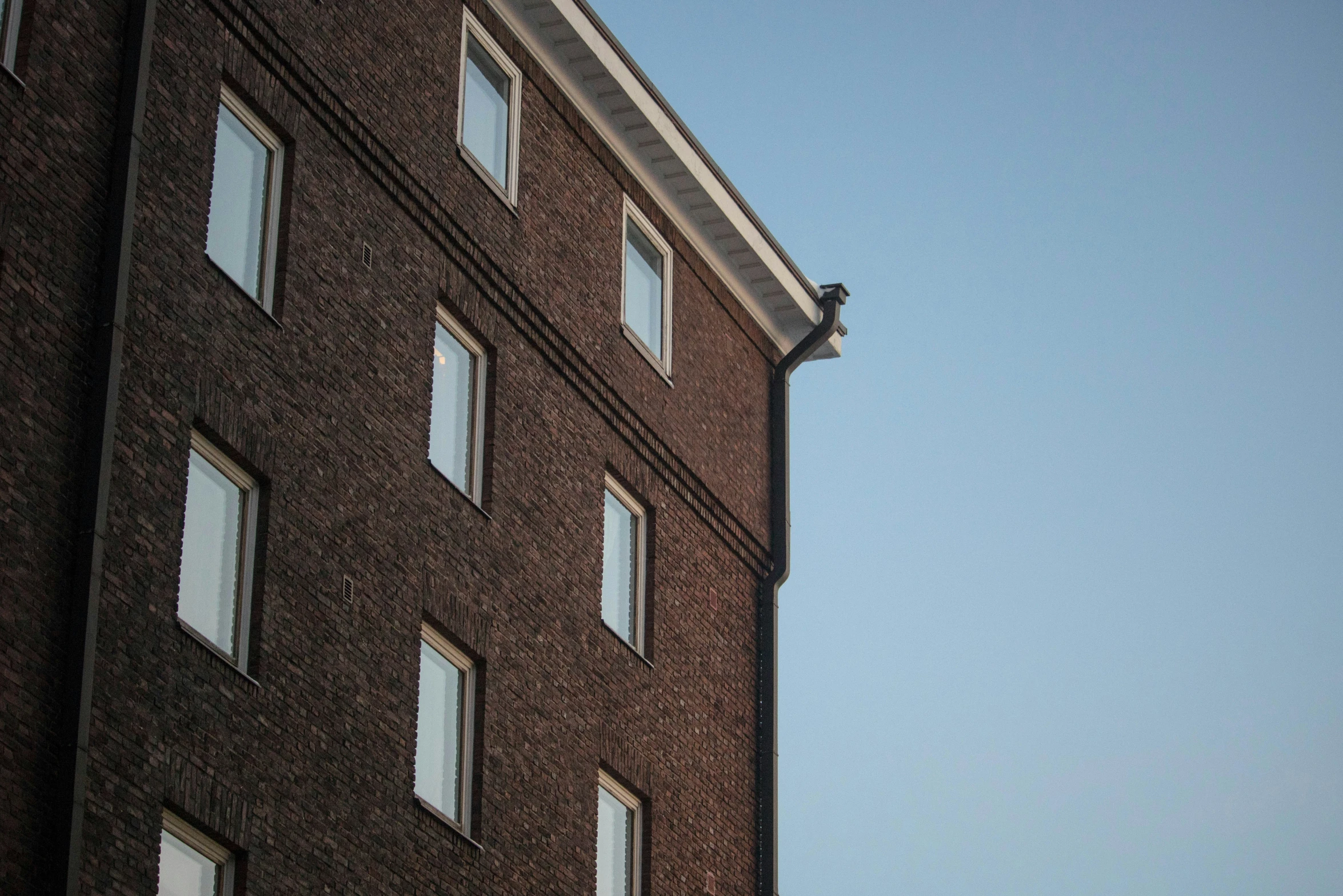 an airplane flying above the windows on a very tall brick building