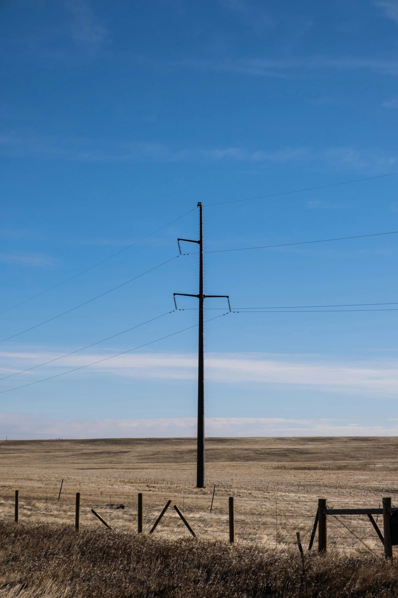 an electric pole standing in the middle of a field