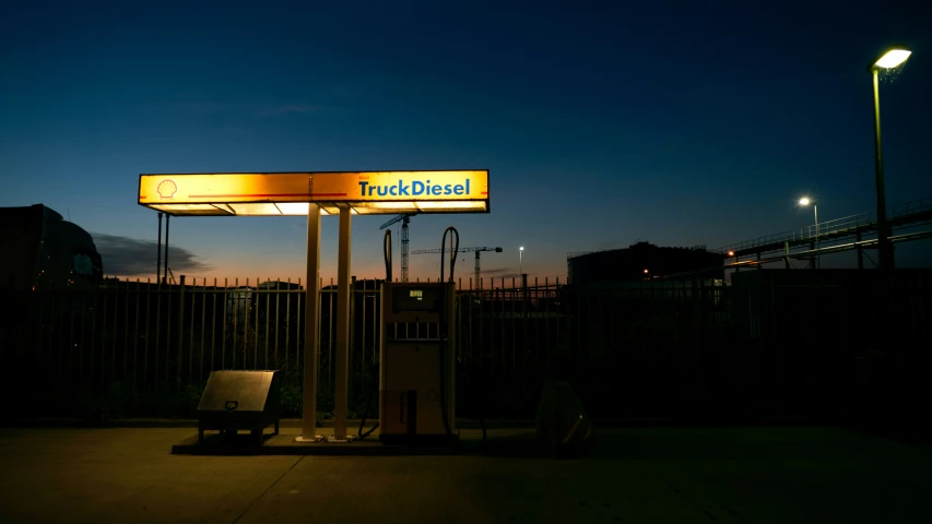 a gas station with a lighted sign next to the road