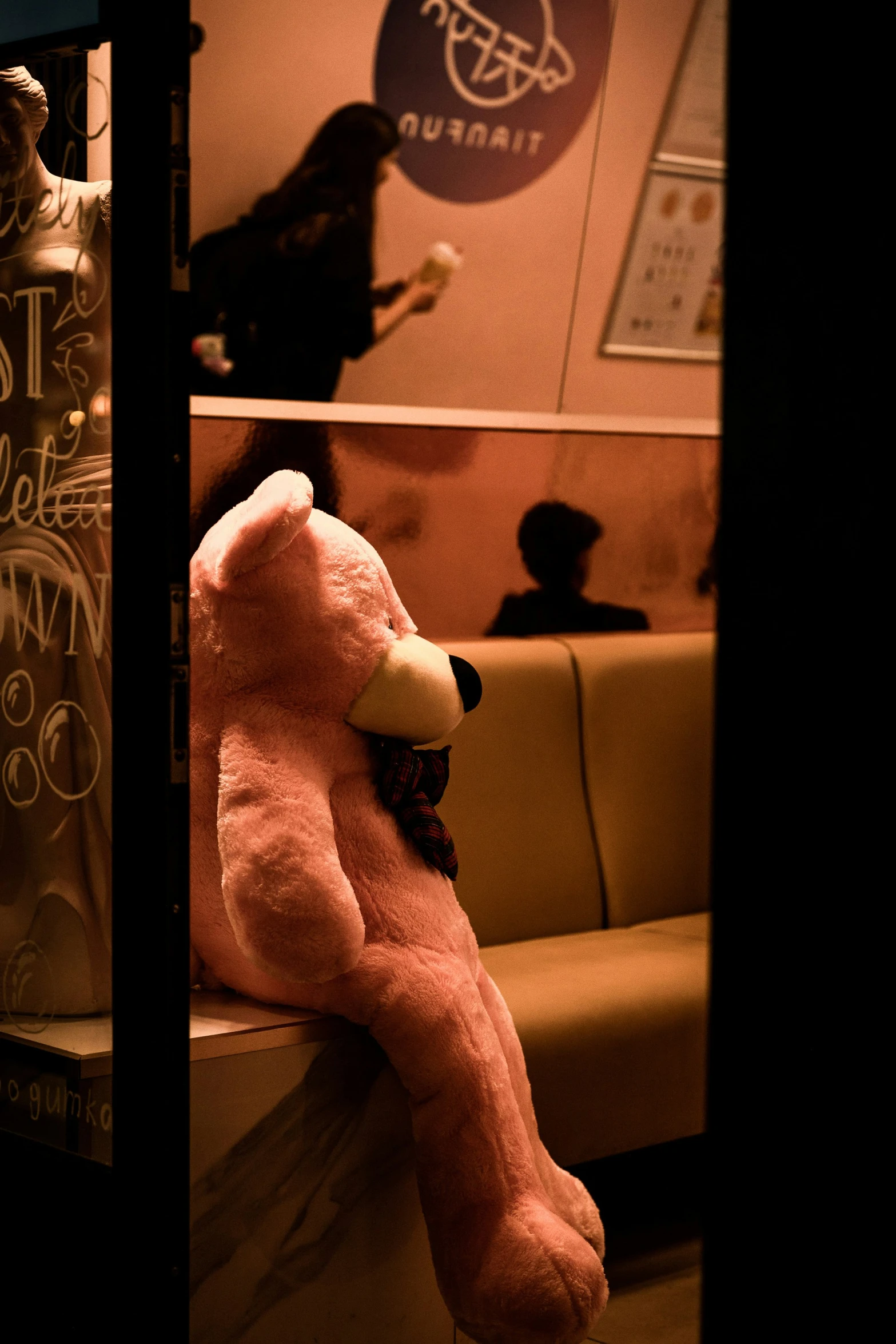 a large pink teddy bear sitting in a window