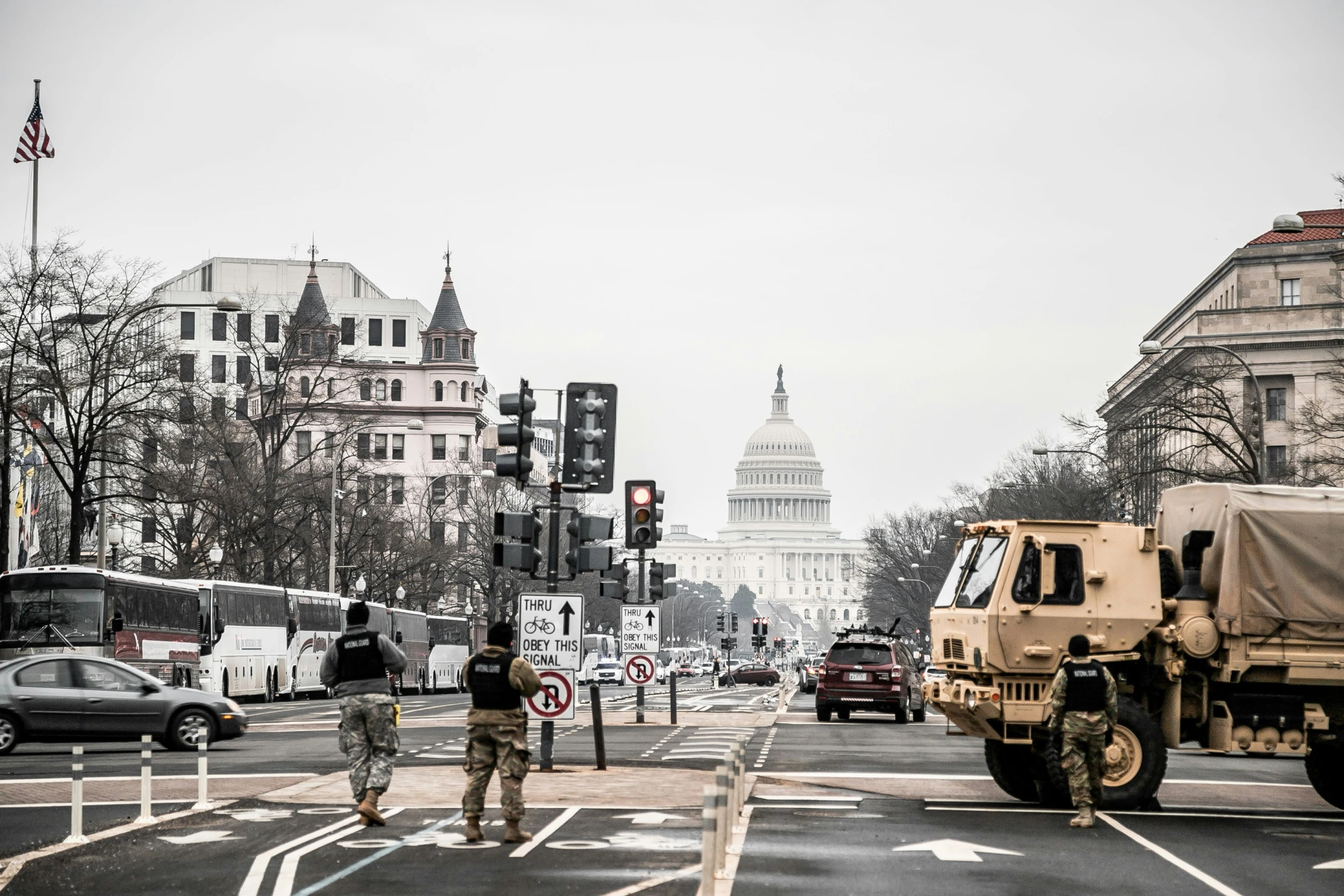 two military trucks are parked at a light