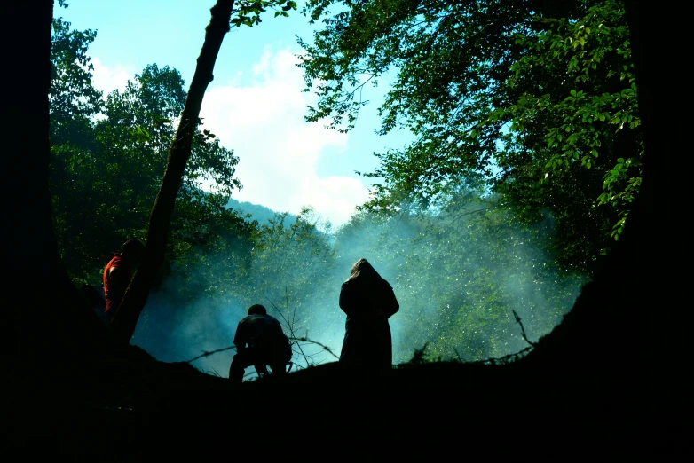 two people in dark shadows and some trees