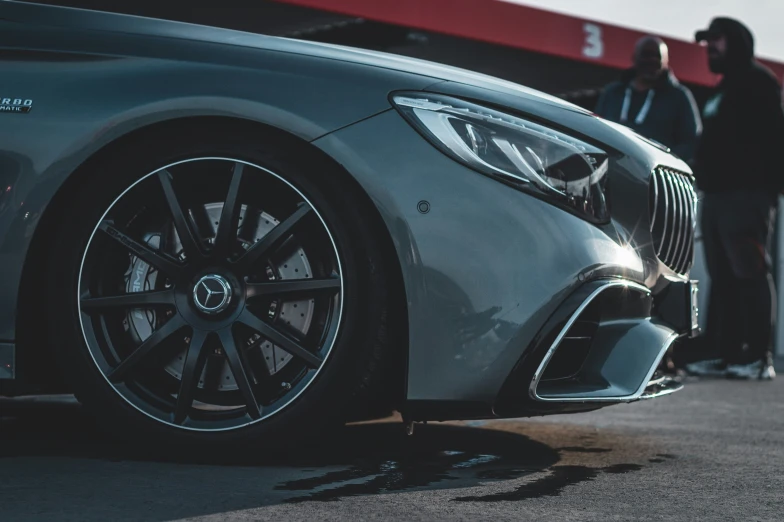 people are waiting outside of a gray mercedes vehicle