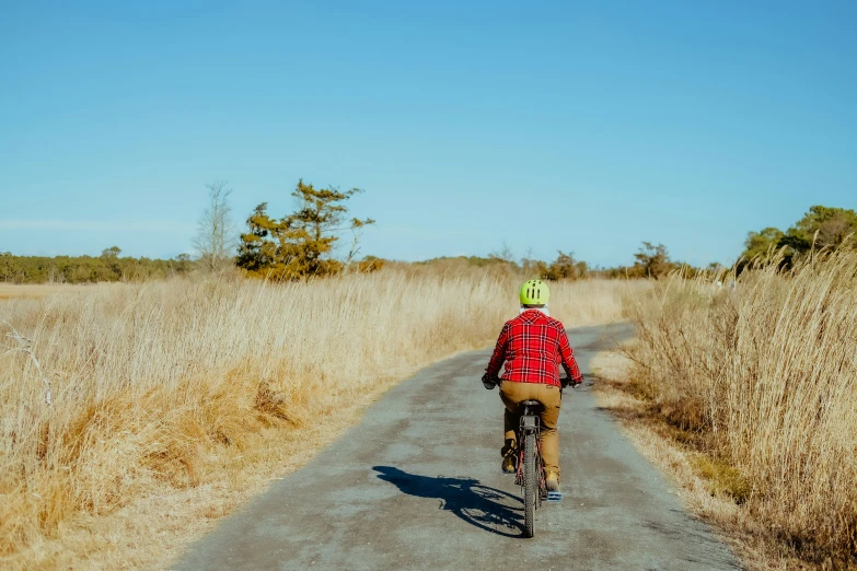 a man riding a bicycle down a dirt road