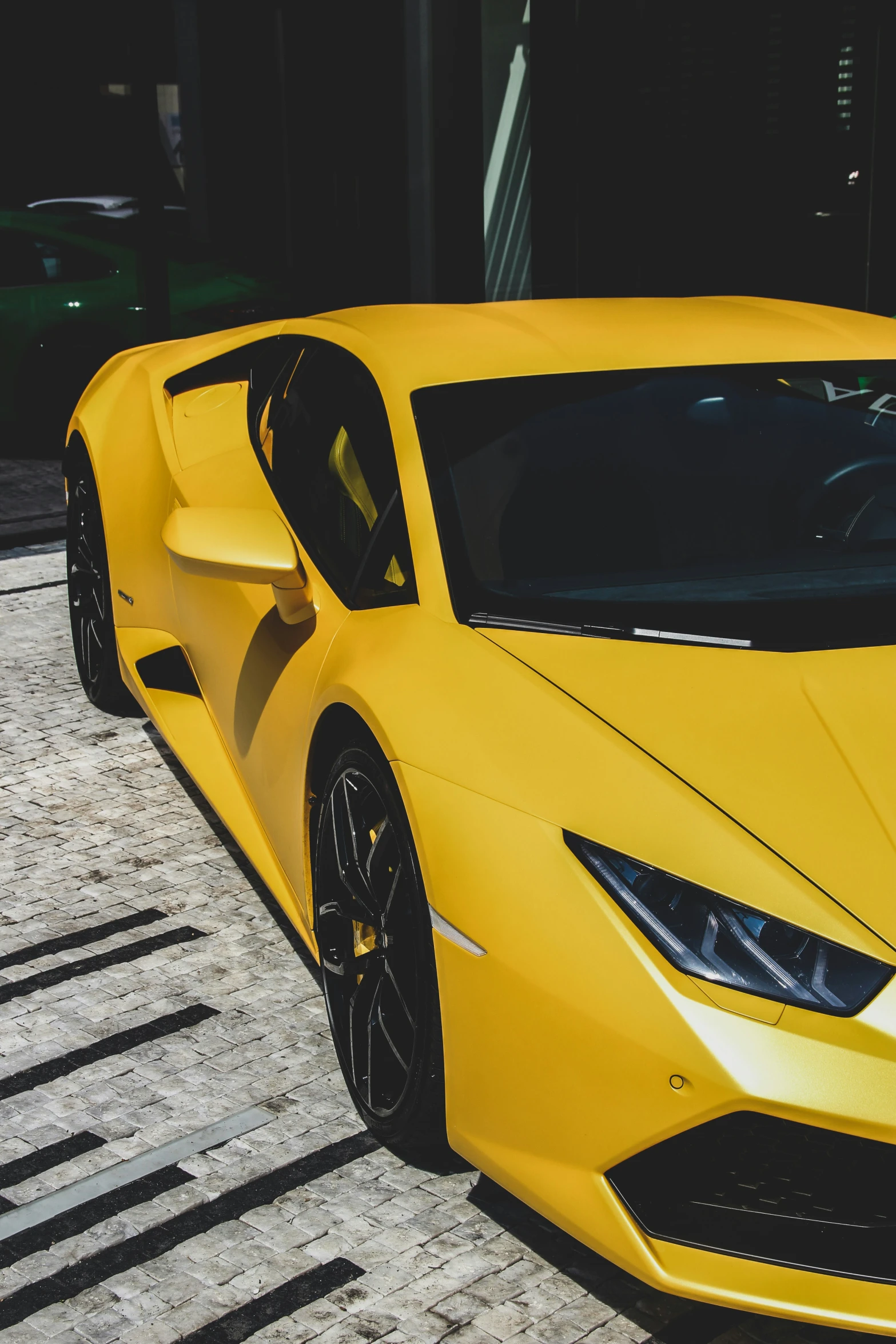 the new, bright yellow sport car is parked on the sidewalk