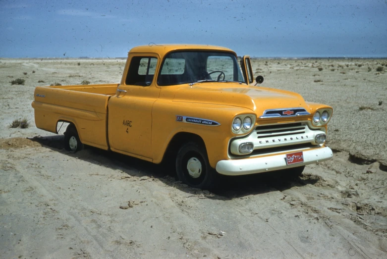 a yellow old fashioned pickup truck in the desert