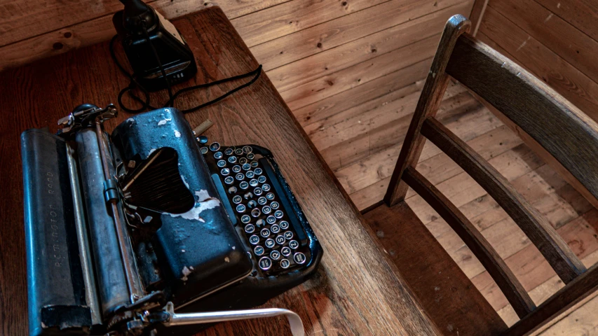 old typewriter sitting on a table and near a chair