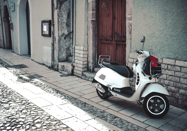 white scooter parked on the street outside a building