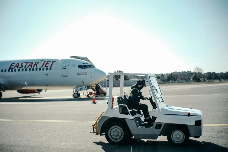 a man driving a vehicle towards an airplane