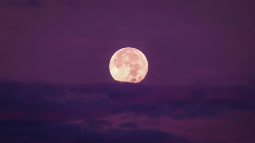 the moon is seen from the clouds at night