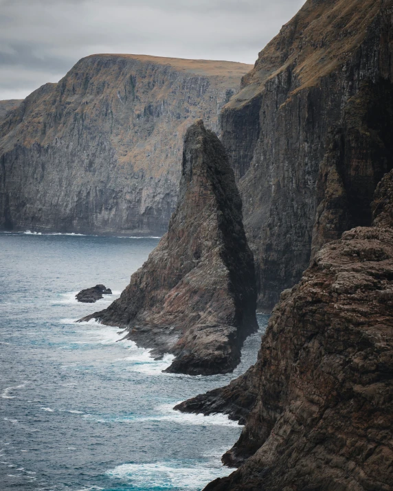 a view of an ocean, cliffs, and rocks from a cliff side