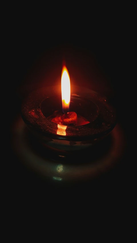 a candle with a glass ashr on it in the dark