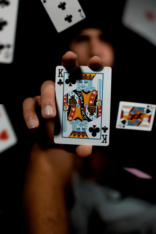 a person holding up two cards while surrounded by playing card suits